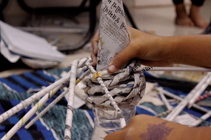 Weaving rolled newspaper during a paper-roll workshop